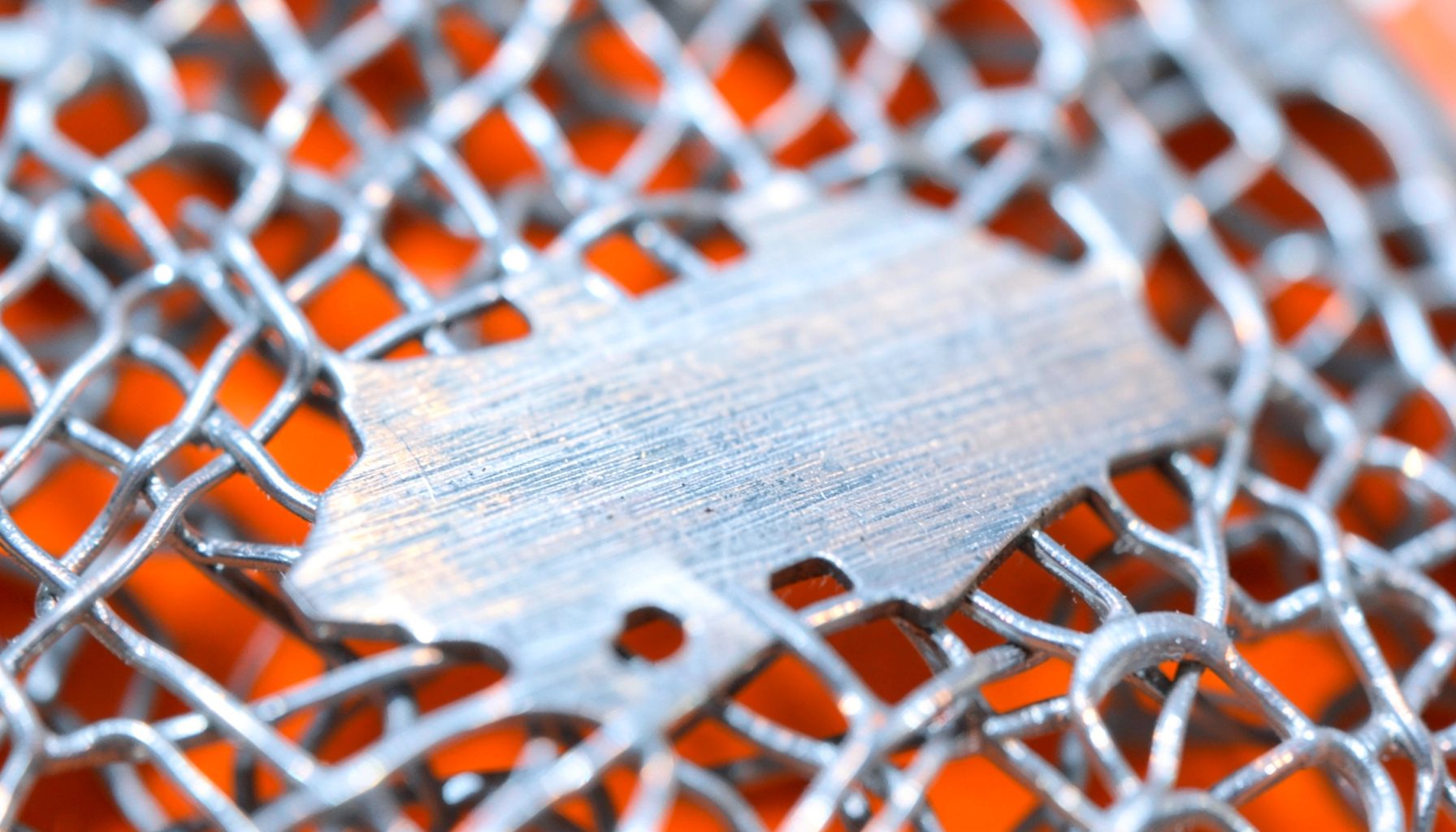 Extreme close-up of brushed stainless steel watch mesh, cool silver tones with subtle horizontal grain texture